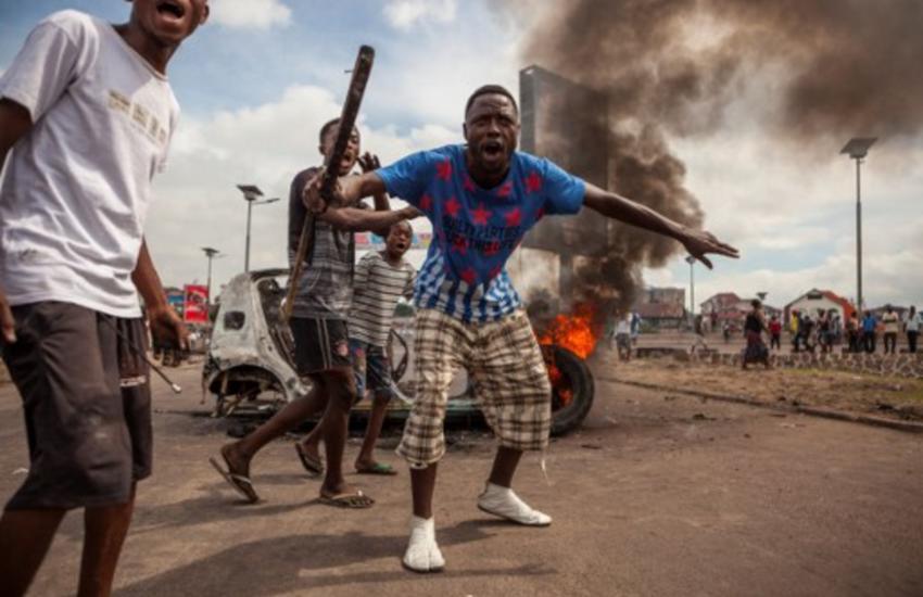 Demonstrators gather in front of a burning car in Kinshasa on September 19, 2016.