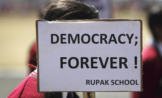 Child holding up sign saying Democracy forever